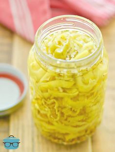 a jar filled with macaroni and cheese sitting on top of a wooden table