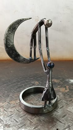 a metal sculpture sitting on top of a wooden table next to a moon and crescent