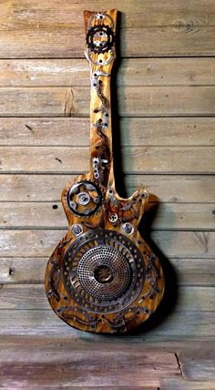 an old guitar hanging on the wall with wood planks in the backround