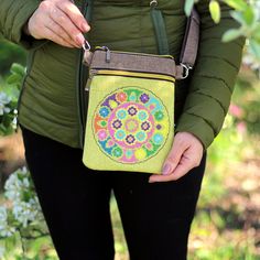 a woman is holding a small purse with flowers on the front and side, while wearing black leggings