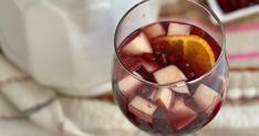 a glass filled with ice and fruit on top of a table