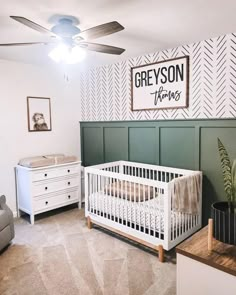 a baby's room with a crib, dressers and a wall sign