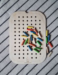 a wooden peg board with colored crayons on it