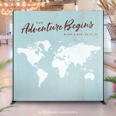 a wooden sign with the words our adventure begins on it and a world map behind it