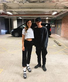 a man and woman standing in an empty parking garage with their arms around each other