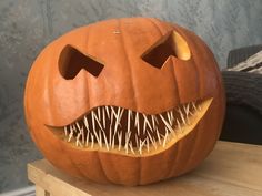 a carved pumpkin with teeth and fangs on it's face, sitting on a table