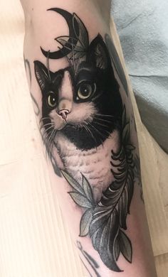 a black and white cat with leaves on it's leg is featured in this tattoo