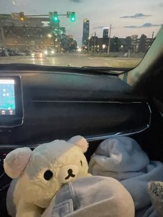 a teddy bear sitting in the passenger seat of a car next to a cell phone