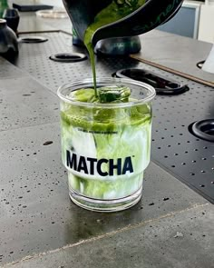 a glass filled with green liquid sitting on top of a table