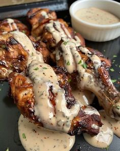 chicken wings covered in sauce and garnished with parsley on a black plate