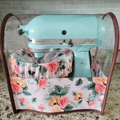 a blue mixer sitting on top of a counter next to a flowery cloth bag