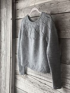 a gray sweater hanging on a wooden wall