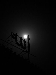 the top of a building with a lit up sign on it's side at night