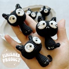 three crocheted black and white cats sitting on top of each other in front of a plate