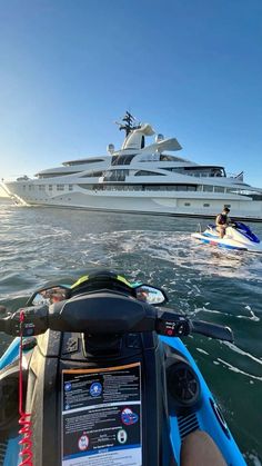 a person riding a jet ski in the water near a large white boat with people on it