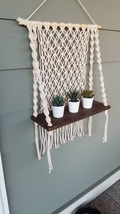 macrame wall hanging with three potted succulents and two white pots