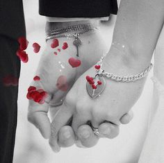 two people holding hands with red petals on them and a key to their heart in the middle