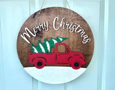 a wooden sign with a red truck and christmas tree on it's front door