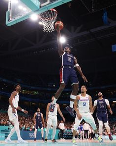 a basketball player dunks the ball in front of his team mates during a game