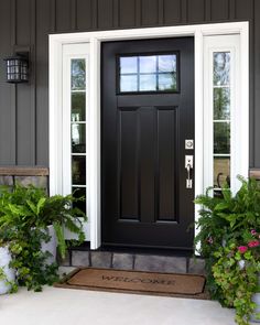 a black front door with white trim and two planters