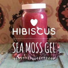 a jar filled with red liquid sitting on top of a wooden table next to a wall