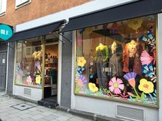 a storefront with flowers and mannequins in the window