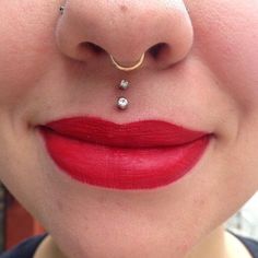 a woman with red lipstick and piercing on her nose