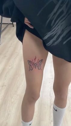 a woman's legs with a butterfly tattoo on her left leg, while wearing white socks