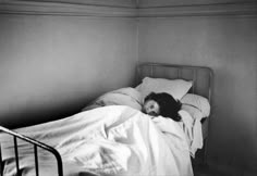 a black and white photo of a woman laying in bed with her head on the pillow