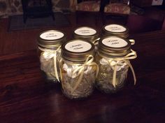 four mason jars with labels on them sitting on a table