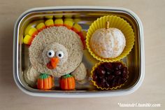 a plastic container with food in it and a turkey decoration on the side, next to an orange pumpkin