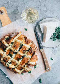 a pizza sitting on top of a wooden cutting board next to a knife and cheese