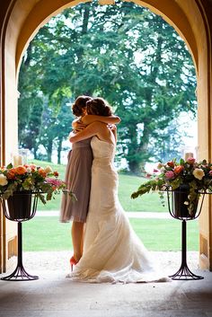 two brides embracing each other in front of an archway