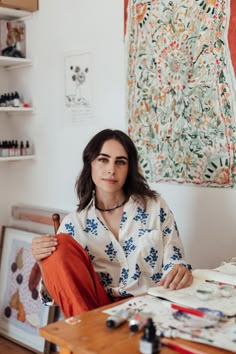 a woman sitting at a table in front of art work