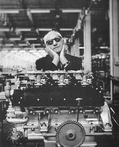 an old photo of a man with sunglasses on his head sitting in front of a large engine