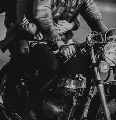 a man riding on the back of a motorcycle down a street next to another person