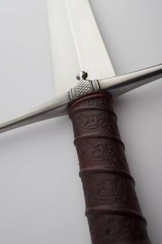 a close up of a knife with a leather sheath on the end and a metal blade sticking out of it