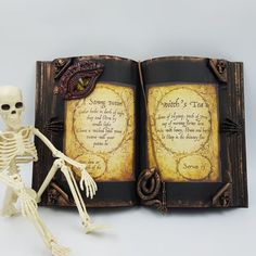 a skeleton sitting in front of an open book with writing on the pages and a small figure next to it