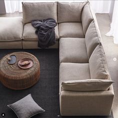 a living room filled with furniture and pillows on top of a carpeted floor next to a window