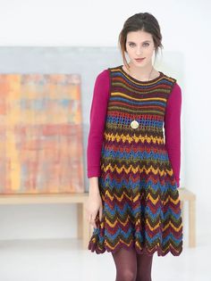 a woman standing in front of a painting wearing a multicolored knitted dress