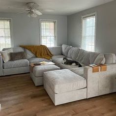 a living room filled with furniture and a cat laying on top of the couches