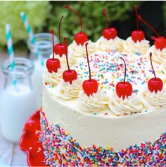 a birthday cake with sprinkles and cherries on the top is ready to be eaten