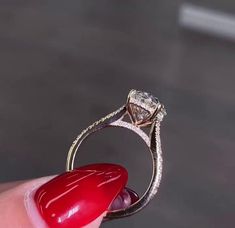 a close up of a person's hand holding a ring with a diamond on it