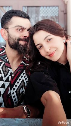 a man and woman sitting next to each other posing for the camera with their arms around each other