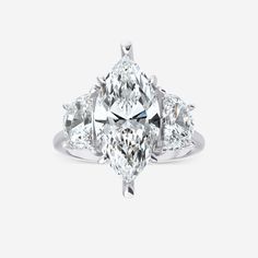 an oval cut diamond ring with three pear shaped diamonds in the center and side stones