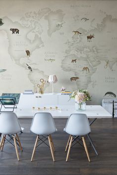 a dining room table with four chairs and a world map on the wall behind it