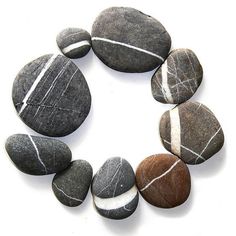 several rocks arranged in a circle on a white surface with lines drawn across the stones