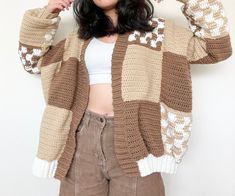 a woman wearing a brown and white knitted cardigan with her hands behind her head