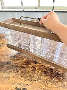 a person holding a plastic container on top of a wooden table