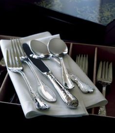 silverware is sitting on top of a white napkin with spoons and forks in it